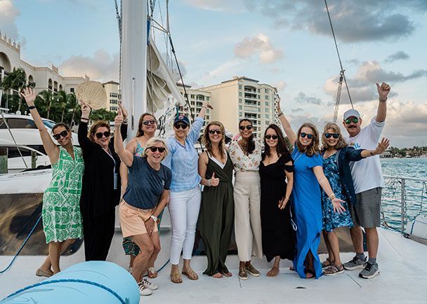 A group of people on a sailboat smiling and waving during a Connoisseurs Connections Conference.