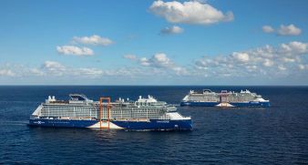 Two large Celebrity Cruises ships sail on calm blue ocean water under a partly cloudy sky.