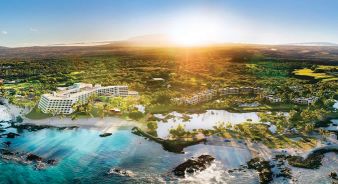 Aerial view of the Mauna Lani coastal resort complex in Kamuela, HI, surrounded by tropical greenery, sandy beaches, and clear blue ocean under a bright sun.