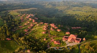Aerial view of Hacienda AltaGracia resort with multiple red-roofed buildings surrounded by green hills and vegetation.
