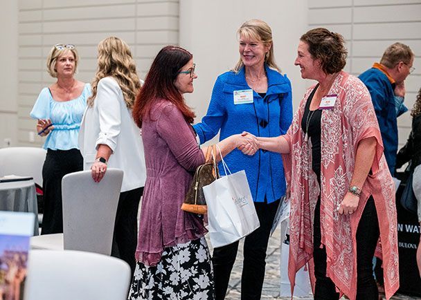 Women shaking hands at a Retreats Resources roadshow.
