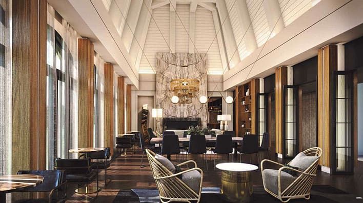 Hotel Hartness, Greenville, SC modern lobby with high vaulted ceiling, marble accent wall, contemporary furniture, large windows, and warm lighting.